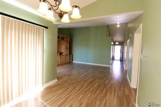 spare room with hardwood / wood-style floors and a chandelier