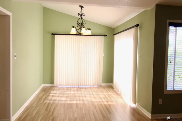 unfurnished room with lofted ceiling, a notable chandelier, and hardwood / wood-style flooring