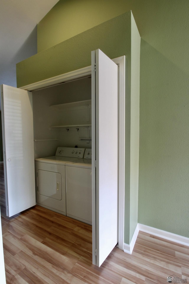 clothes washing area with washer and dryer and light hardwood / wood-style flooring