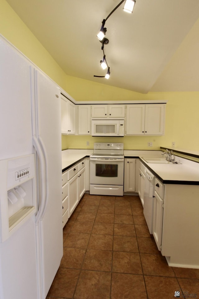 kitchen with sink, white cabinetry, vaulted ceiling, dark tile patterned floors, and white appliances