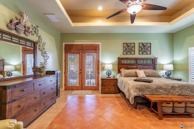 bedroom with french doors, ceiling fan, a tray ceiling, and light tile patterned flooring