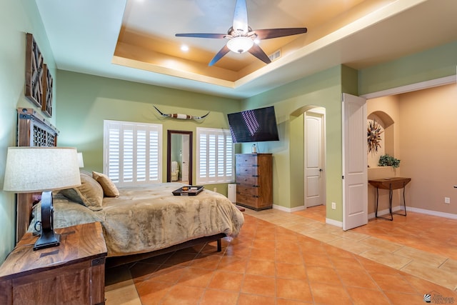 bedroom featuring a tray ceiling, ceiling fan, and light tile patterned flooring