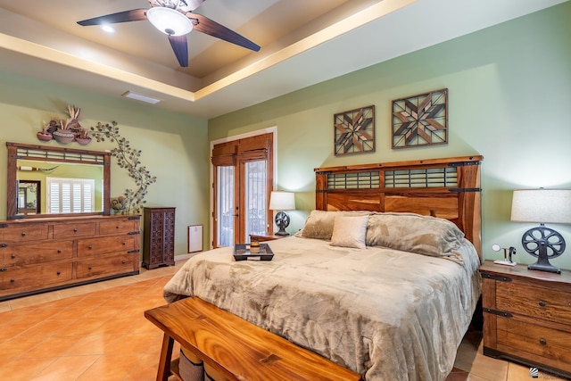 bedroom with light tile patterned floors, ceiling fan, and a tray ceiling