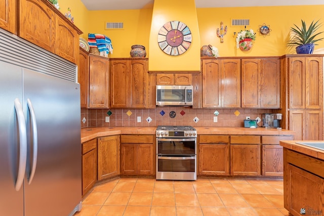 kitchen featuring stainless steel appliances, light tile patterned flooring, and decorative backsplash