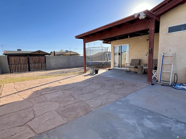 view of patio with a trampoline and fence