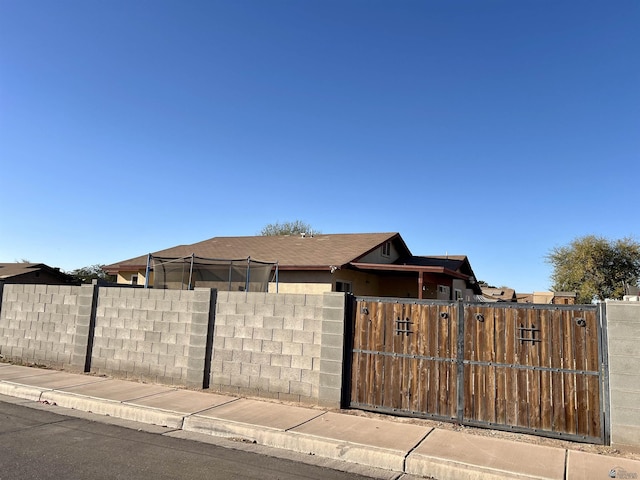 view of front of property with roof with shingles, a fenced front yard, and a gate