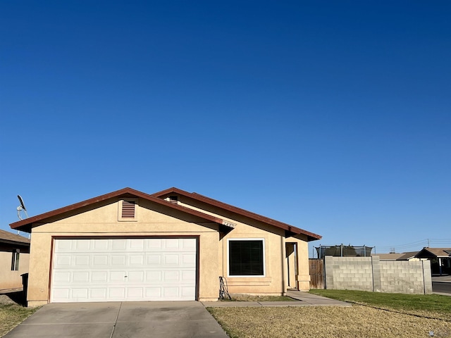 view of front of property featuring driveway, an attached garage, fence, and stucco siding