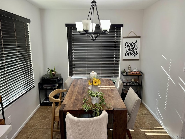 tiled dining space featuring a chandelier and baseboards