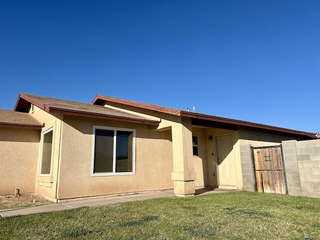 back of property featuring a yard and stucco siding