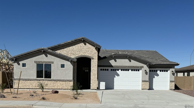 view of front facade featuring an attached garage, stone siding, a tile roof, and stucco siding