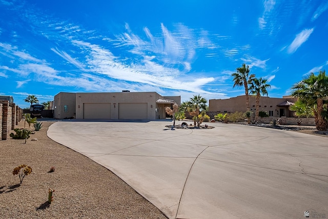 pueblo revival-style home featuring a garage, driveway, and stucco siding