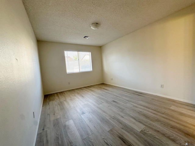 unfurnished room featuring a textured ceiling and light wood-type flooring