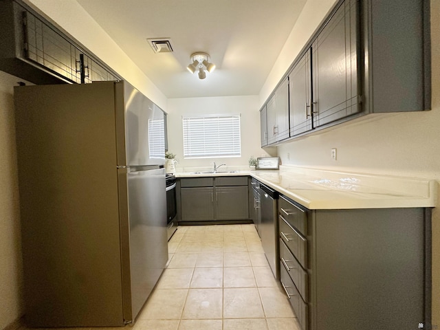 kitchen featuring sink, stainless steel appliances, gray cabinetry, and light tile patterned flooring