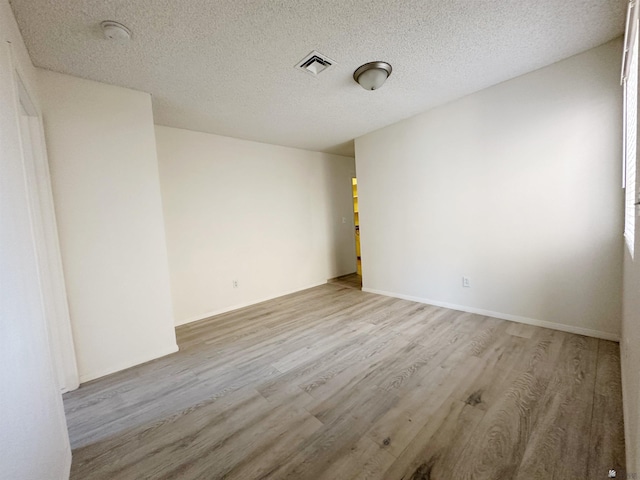 spare room with light hardwood / wood-style floors and a textured ceiling