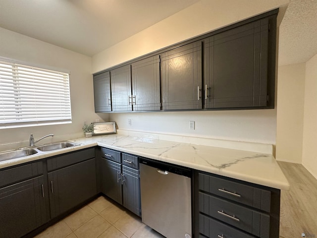 kitchen featuring light stone countertops, light tile patterned flooring, stainless steel dishwasher, and sink