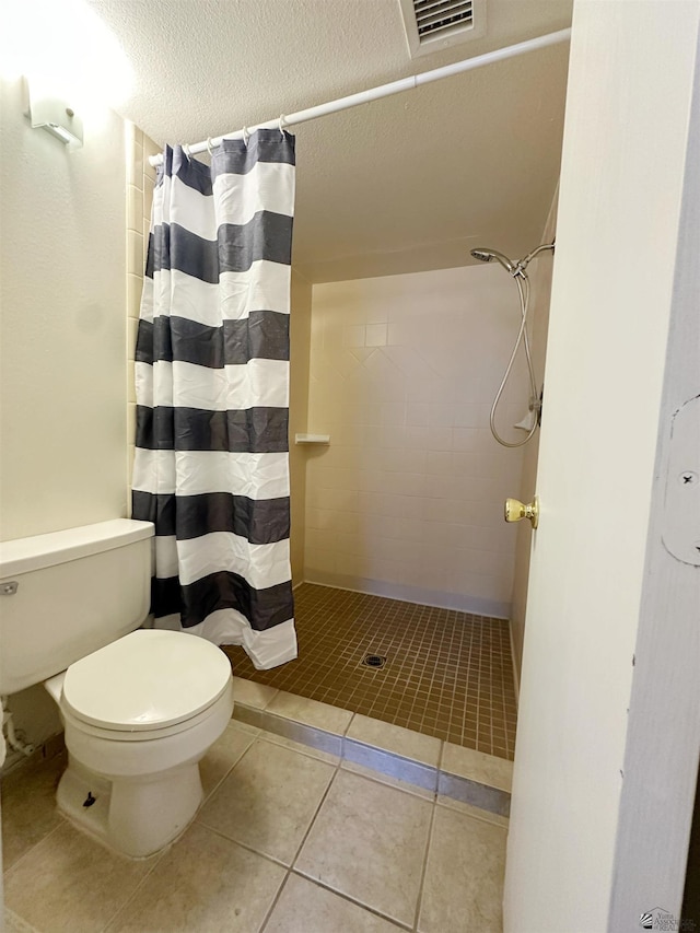 bathroom featuring tile patterned flooring, a textured ceiling, toilet, and curtained shower