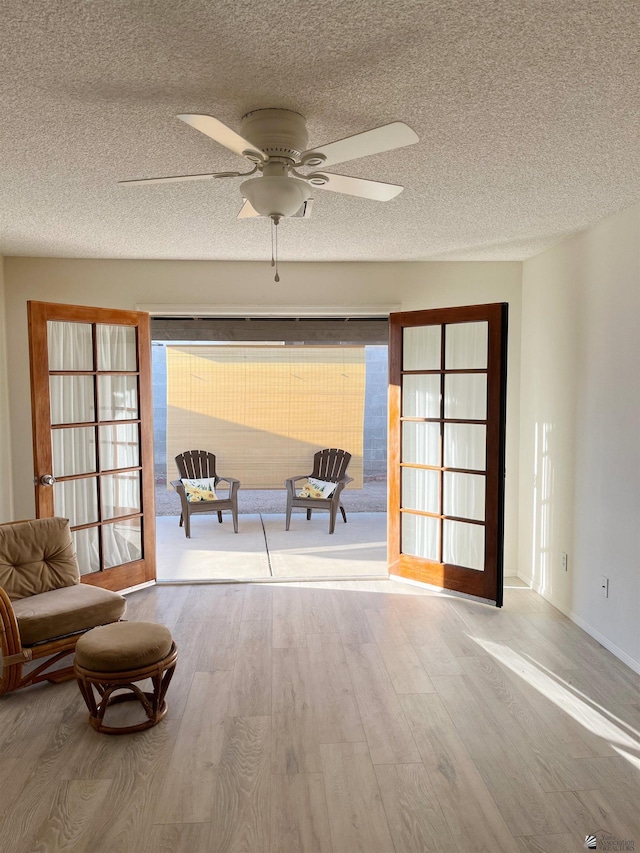 interior space featuring french doors, light wood-type flooring, a textured ceiling, and ceiling fan