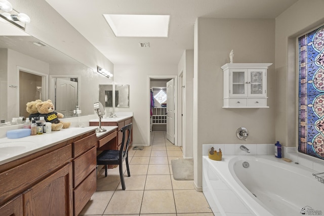 bathroom with a skylight, a bathtub, vanity, and tile patterned floors