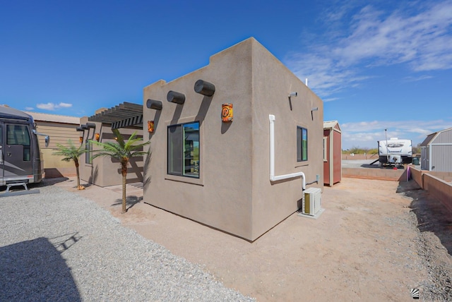 view of property exterior with a pergola and stucco siding