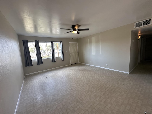 empty room with visible vents, a ceiling fan, and baseboards