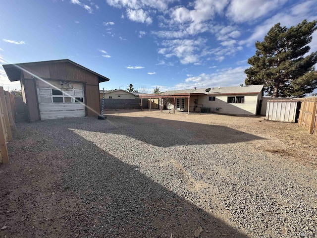 back of property with a detached garage, an outbuilding, a fenced backyard, and driveway