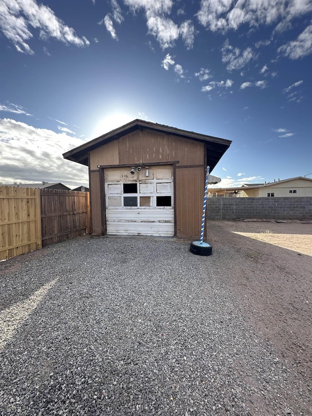 detached garage with gravel driveway and fence