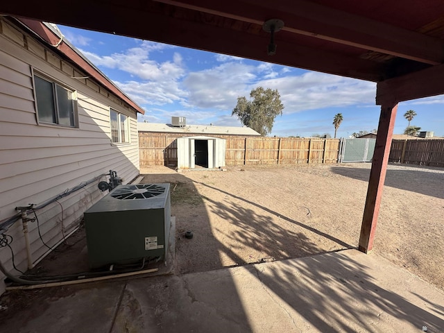 view of patio / terrace with a fenced backyard, an outbuilding, and central AC