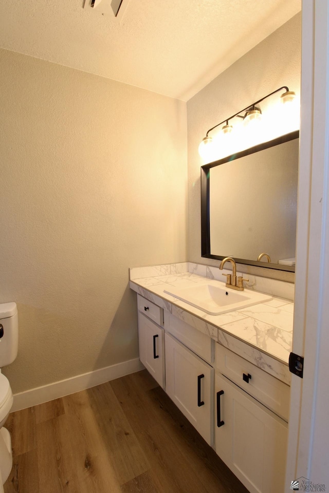 bathroom with toilet, vanity, and hardwood / wood-style flooring