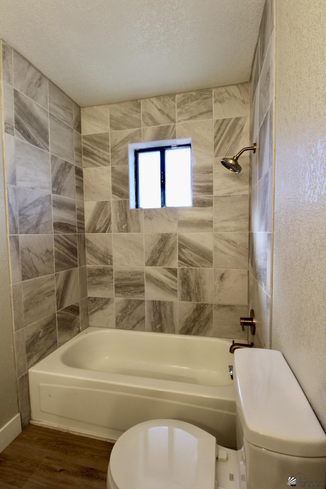 bathroom featuring toilet, tiled shower / bath combo, a textured ceiling, and hardwood / wood-style floors