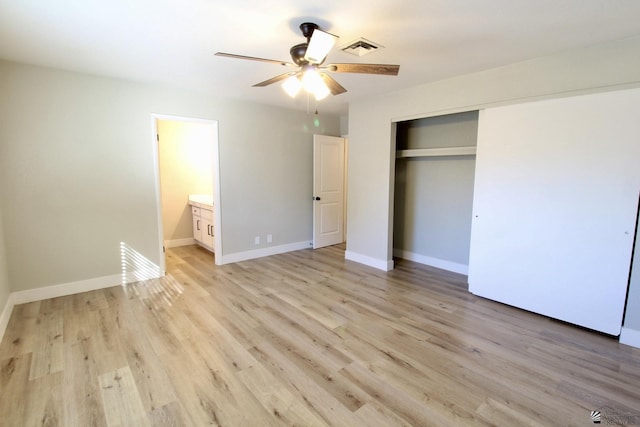 unfurnished bedroom featuring ensuite bath, a closet, ceiling fan, and light wood-type flooring