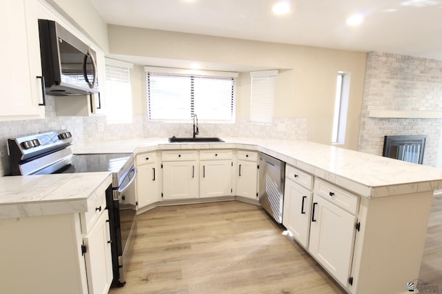 kitchen featuring appliances with stainless steel finishes, white cabinets, sink, and kitchen peninsula