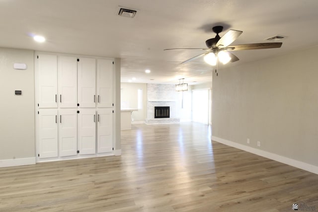 unfurnished living room featuring a brick fireplace, ceiling fan, and light hardwood / wood-style floors