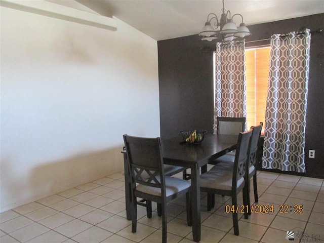 dining space featuring a notable chandelier, light tile patterned floors, and vaulted ceiling