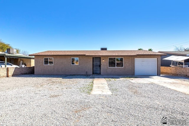 ranch-style house featuring concrete driveway, central AC, an attached garage, and stucco siding