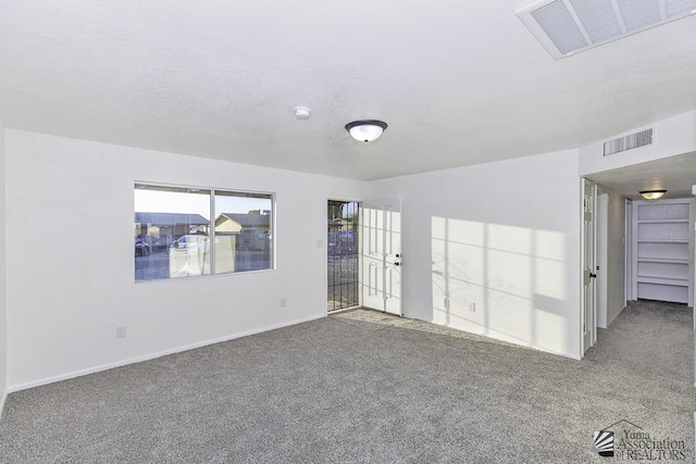 carpeted spare room featuring visible vents, a textured ceiling, and baseboards