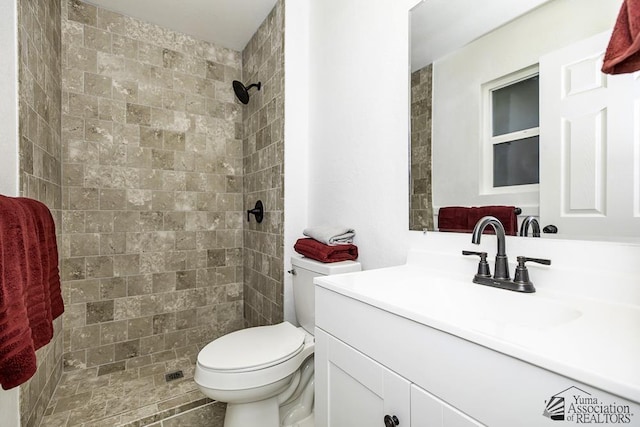 full bath with a tile shower, vanity, and toilet