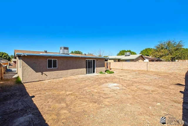 rear view of property featuring fence and stucco siding