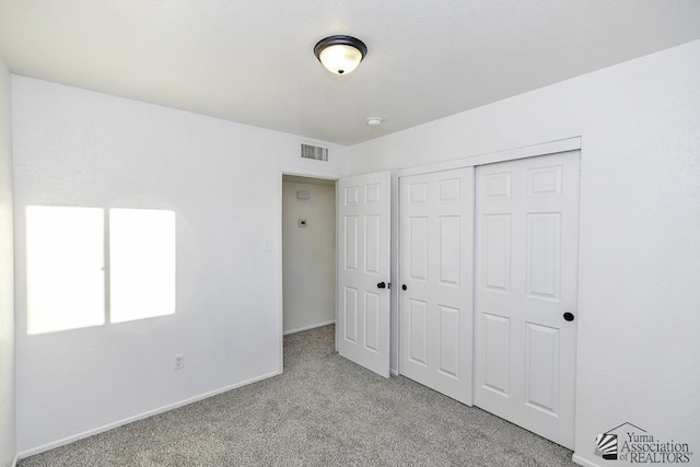 unfurnished bedroom featuring light carpet, a closet, visible vents, and baseboards