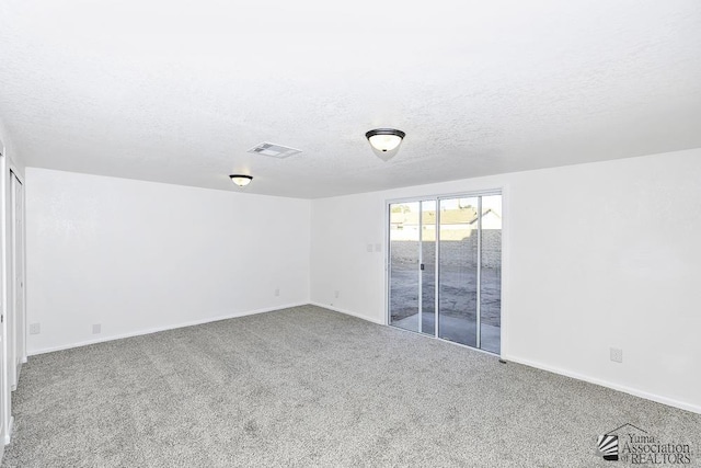 carpeted spare room featuring a textured ceiling, visible vents, and baseboards