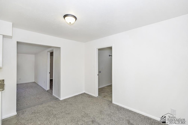 carpeted empty room featuring baseboards