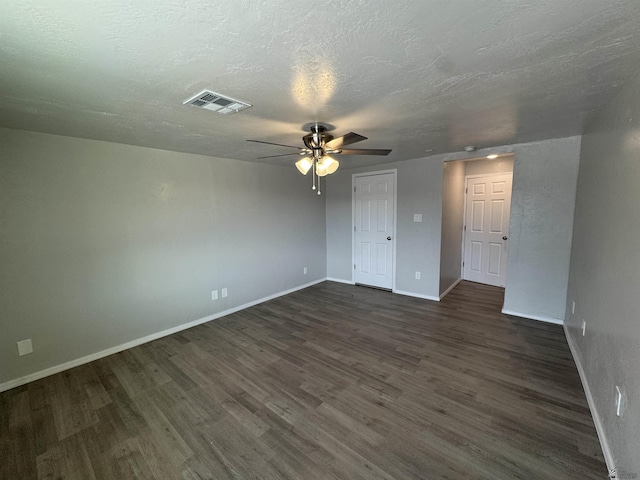 empty room featuring visible vents, a textured ceiling, dark wood-type flooring, and baseboards