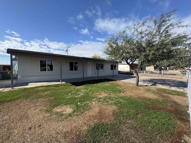 view of front of house with fence, a front yard, and a patio area