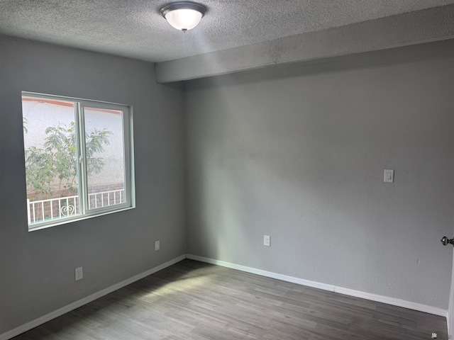 empty room featuring a textured ceiling, baseboards, and wood finished floors