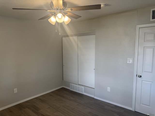 unfurnished bedroom featuring a closet, visible vents, dark wood-type flooring, and baseboards