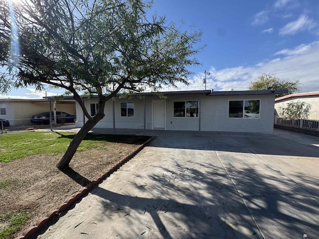 ranch-style house featuring stucco siding and fence