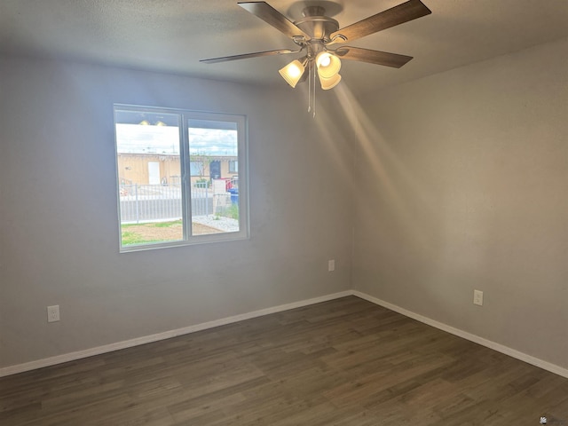 empty room featuring dark wood finished floors, a textured ceiling, a ceiling fan, and baseboards