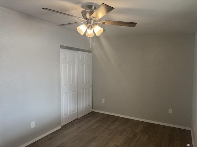 unfurnished bedroom featuring a closet, ceiling fan, dark wood-type flooring, and baseboards