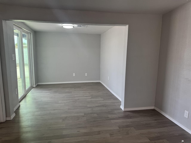 spare room with visible vents, baseboards, and dark wood-style flooring