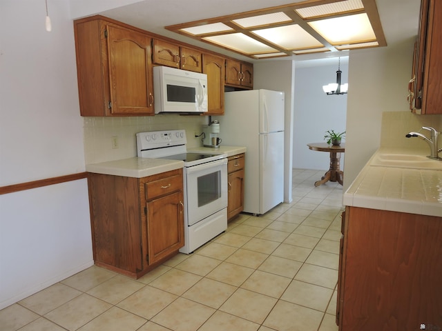 kitchen featuring white appliances, pendant lighting, decorative backsplash, sink, and an inviting chandelier