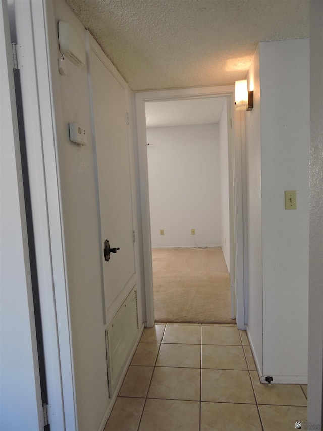 hall featuring light colored carpet and a textured ceiling